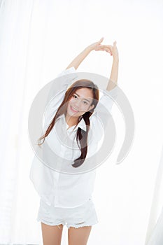 Beautiful young asian woman stretch and relax standing in bed after wake up morning at bedroom.