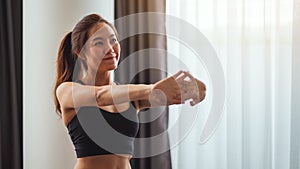 A beautiful young asian woman stretching her arms to warm up before workout at home