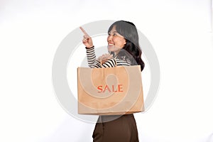 Beautiful young Asian woman on sweater cloth pointing up to copy space and looking at camera with smile face and sale shopping