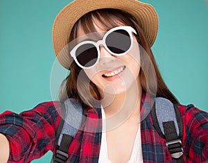 Beautiful young asian woman taking selfie with camera for relax in vacation isolated on blue background