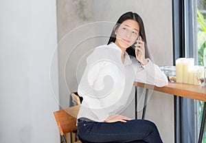 Beautiful young asian woman talking phone and smile in the coffee shop.