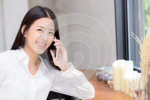 Beautiful young asian woman talking phone and smile in the coffee shop