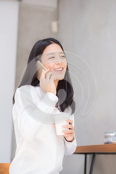 Beautiful young asian woman talking phone and smile in the coffee shop.