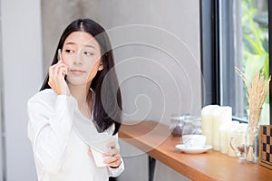 Beautiful young asian woman talking phone and smile in the coffee shop.