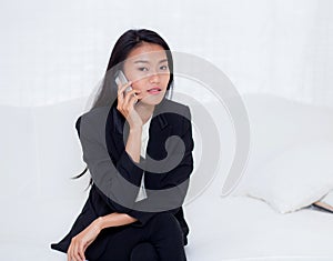 Beautiful young asian woman talking phone and smile in the living room, businesswoman sitting on sofa