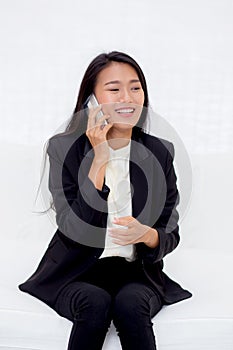 Beautiful young asian woman talking phone and smile in the living room, businesswoman sitting on sofa