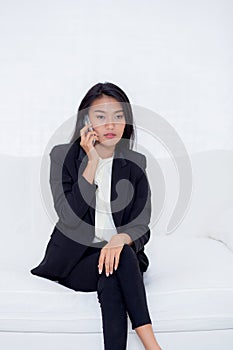 Beautiful young asian woman talking phone and smile in the living room, businesswoman sitting on sofa