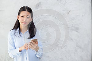 Beautiful young asian woman talking phone and smile standing on cement background