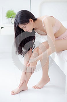 Beautiful young asian woman touch skin leg smooth with cream and lotion for hydration and smooth