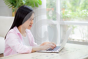 Beautiful young asian woman typing keyboard on laptop computer on desk at home, businesswoman working online.