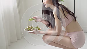 Beautiful young asian woman in underwear with figure perfect eating organic vegetable with salad for breakfast.