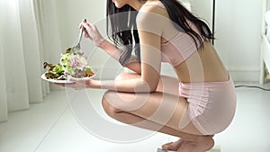 Beautiful young asian woman in underwear with figure perfect eating organic vegetable with salad for breakfast in the home