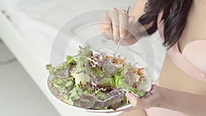 Beautiful young asian woman in underwear with figure perfect eating organic vegetable with salad for breakfast in the home