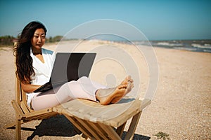 Beautiful young asian woman using her laptop on the beach