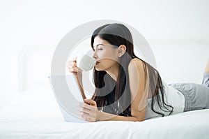 Beautiful young Asian woman using tablet and enjoying a cup of c