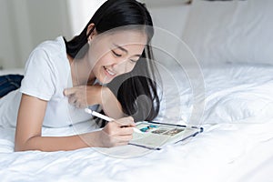 Beautiful young Asian woman watching social online . Asia girl are cute fun and happy on the bed at her home.