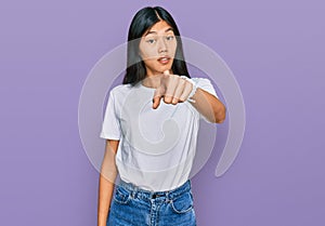 Beautiful young asian woman wearing casual white t shirt pointing displeased and frustrated to the camera, angry and furious with