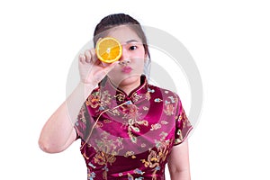 Beautiful Young asian woman wearing chinese dress traditional cheongsam or qipao. Pretty Girl Touching her Face with juicy orange