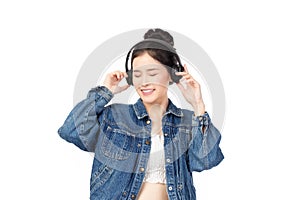 Beautiful young asian woman wearing jeans joyful listening to music on headphones isolated on white background studio portrait