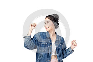 Beautiful young asian woman wearing jeans joyful listening to music on headphones isolated on white background studio portrait