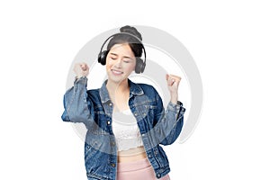 Beautiful young asian woman wearing jeans joyful listening to music on headphones isolated on white background studio portrait