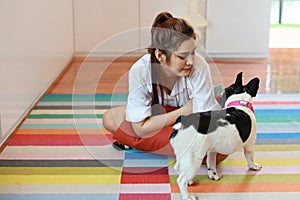 Beautiful young asian woman wearing white shirt and holding red pillow who sitting and playing with her cute dog with happy and