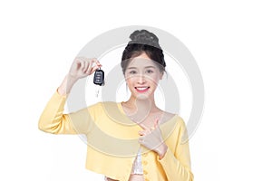 Beautiful young Asian woman wearing yellow shirt feeling happy and smile holding the keys of the car on white background