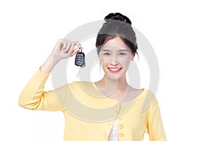 Beautiful young Asian woman wearing yellow shirt feeling happy and smile holding the keys of the car on white background