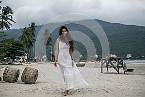 Beautiful young asian woman in white dress walking on the beach.