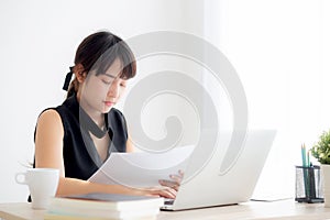 Beautiful young asian woman working and typing with laptop computer at office, businesswoman looking graph diagram analysis statis