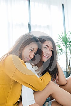 Beautiful young asian women LGBT lesbian couple sitting on bed hugging and smiling together in bedroom at home.