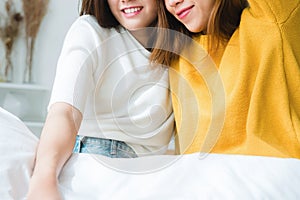 Beautiful young asian women LGBT lesbian couple sitting on bed hugging and smiling together in bedroom at home.