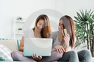 Beautiful young asian women LGBT lesbian couple sitting on sofa buying online using laptop a computer and credit card.