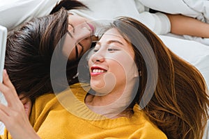 Beautiful young asian women LGBT lesbian happy couple hugging and smiling while lying together in bed.