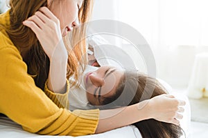 Beautiful young asian women LGBT lesbian happy couple hugging and smiling while lying together in bed under blanket at home.