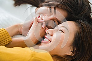 Beautiful young asian women LGBT lesbian happy couple hugging and smiling while lying together in bed under blanket at home.