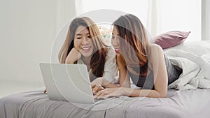 Beautiful young asian women LGBT lesbian happy couple sitting on bed hug and using laptop computer together bedroom at home. LGBT