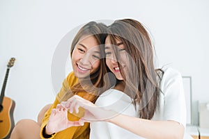 Beautiful young asian women LGBT lesbian happy couple sitting on bed hugging and smiling together in bedroom at home.