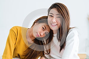 Beautiful young asian women LGBT lesbian happy couple sitting on bed hugging and smiling together in bedroom at home.
