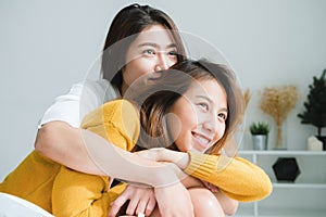 Beautiful young asian women LGBT lesbian happy couple sitting on bed hugging and smiling together in bedroom at home.