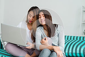 Beautiful young asian women LGBT lesbian happy couple sitting on sofa buying online using laptop in living room at home.