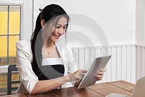 Beautiful young Asian working with tablet computer at office desk or co working space