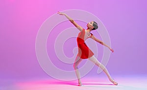 Beautiful young ballerina on a white background. The ballerina is dressed in a red leotard, pink leotards, pointe shoes