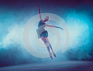 Beautiful young ballet dancer jumping on a lilac background.