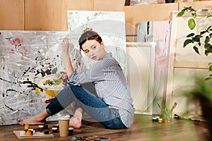 beautiful young barefoot artist sitting on floor and painting picture photo