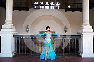 Beautiful young belly dancer is posing for the camera in a photo shoot. The woman is beautiful and dressed in traditional clothes