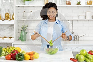 Beautiful young black girl preparing vegetable salad