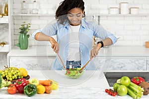 Beautiful young black girl preparing vegetable salad