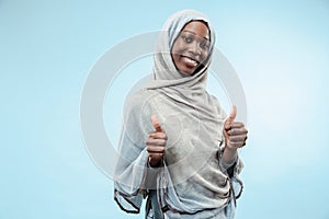 The beautiful young black muslim girl wearing gray hijab, with a happy smile on her face.