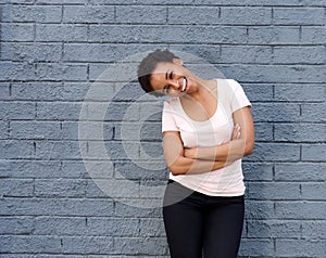 Beautiful young black woman laughing against gray wall